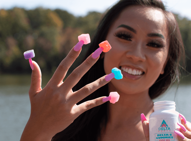 Girl smiling while holding delta 8 gummies flavors in hand