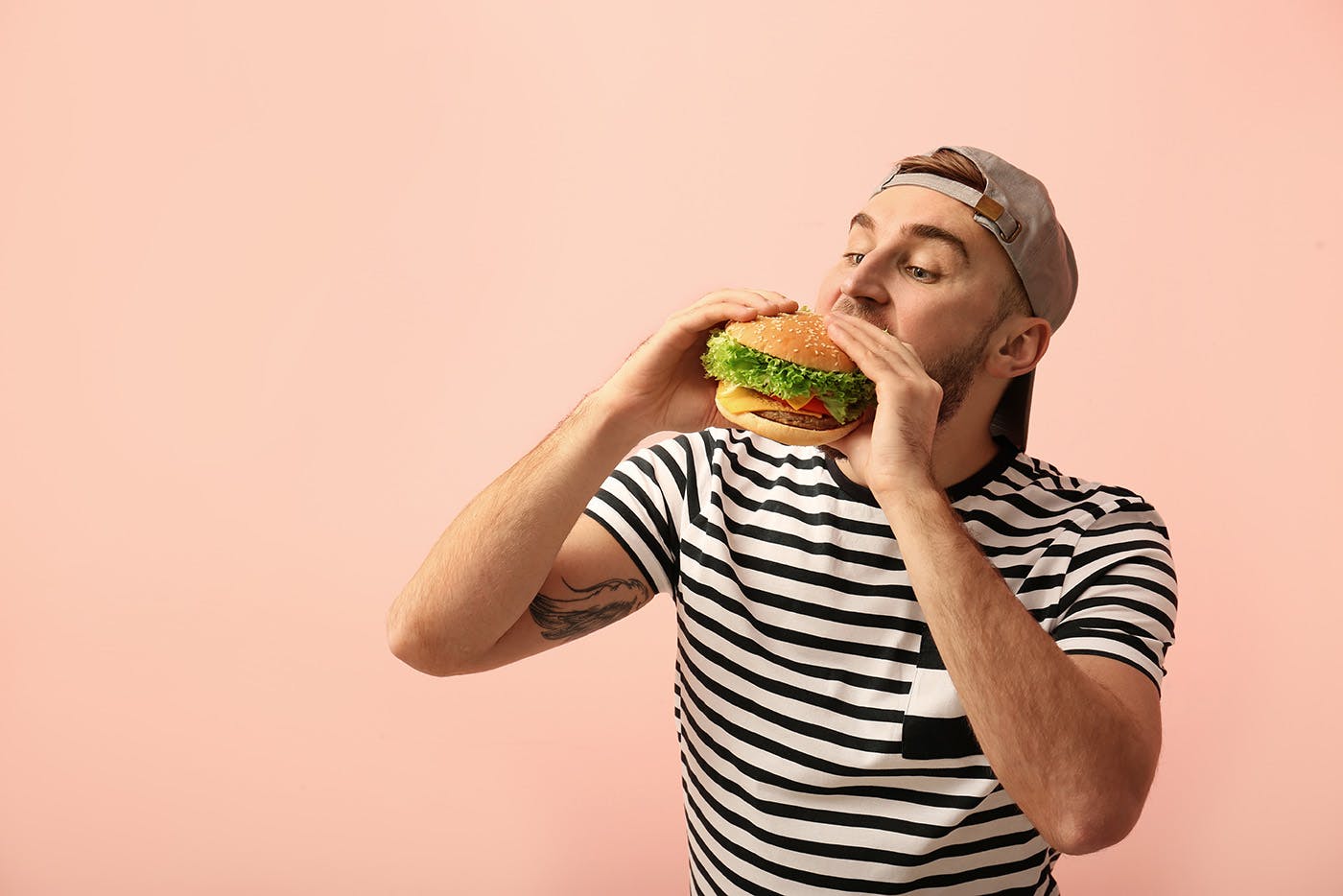 Person eating a burger on pink background