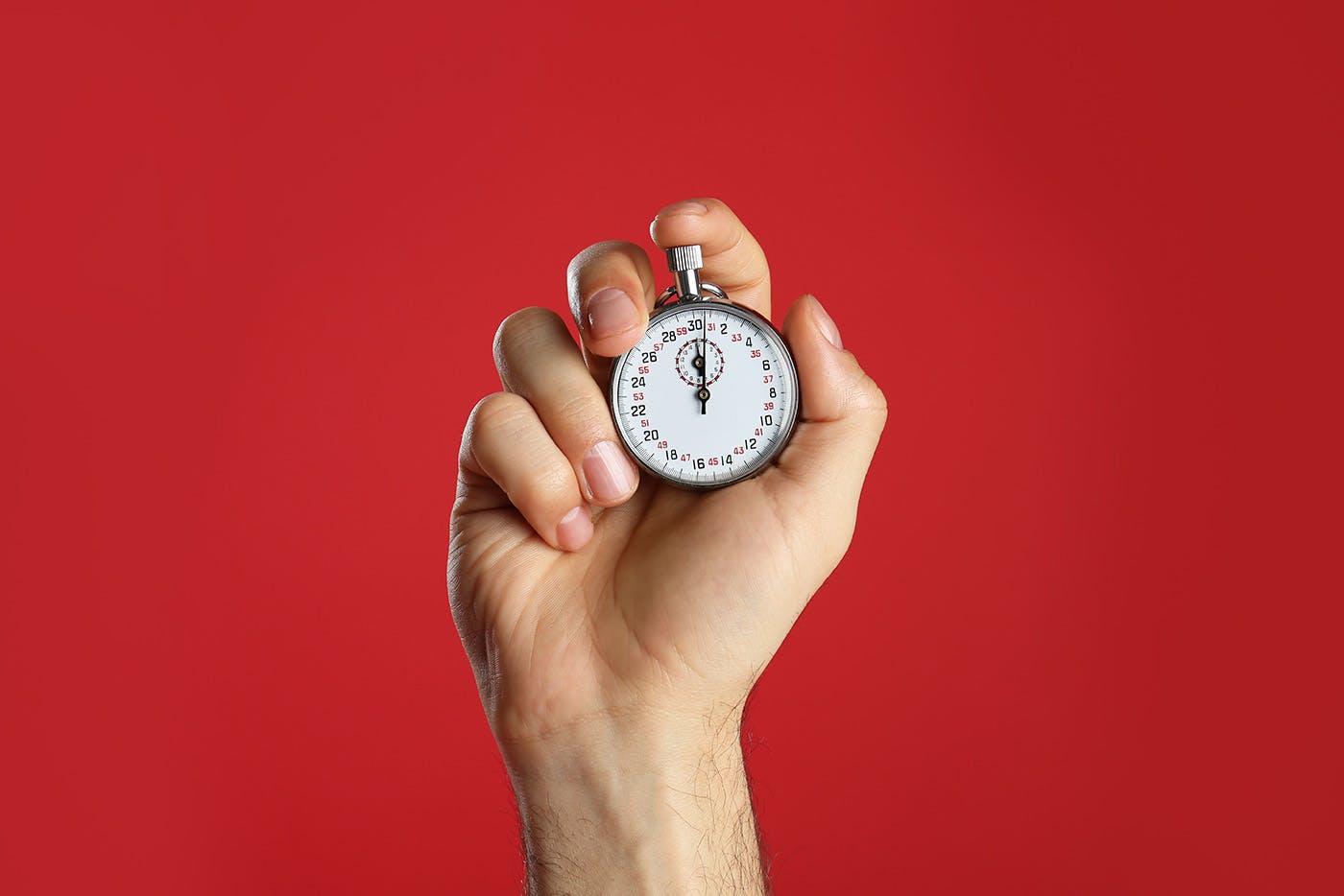Stopwatch on red background being held in hand